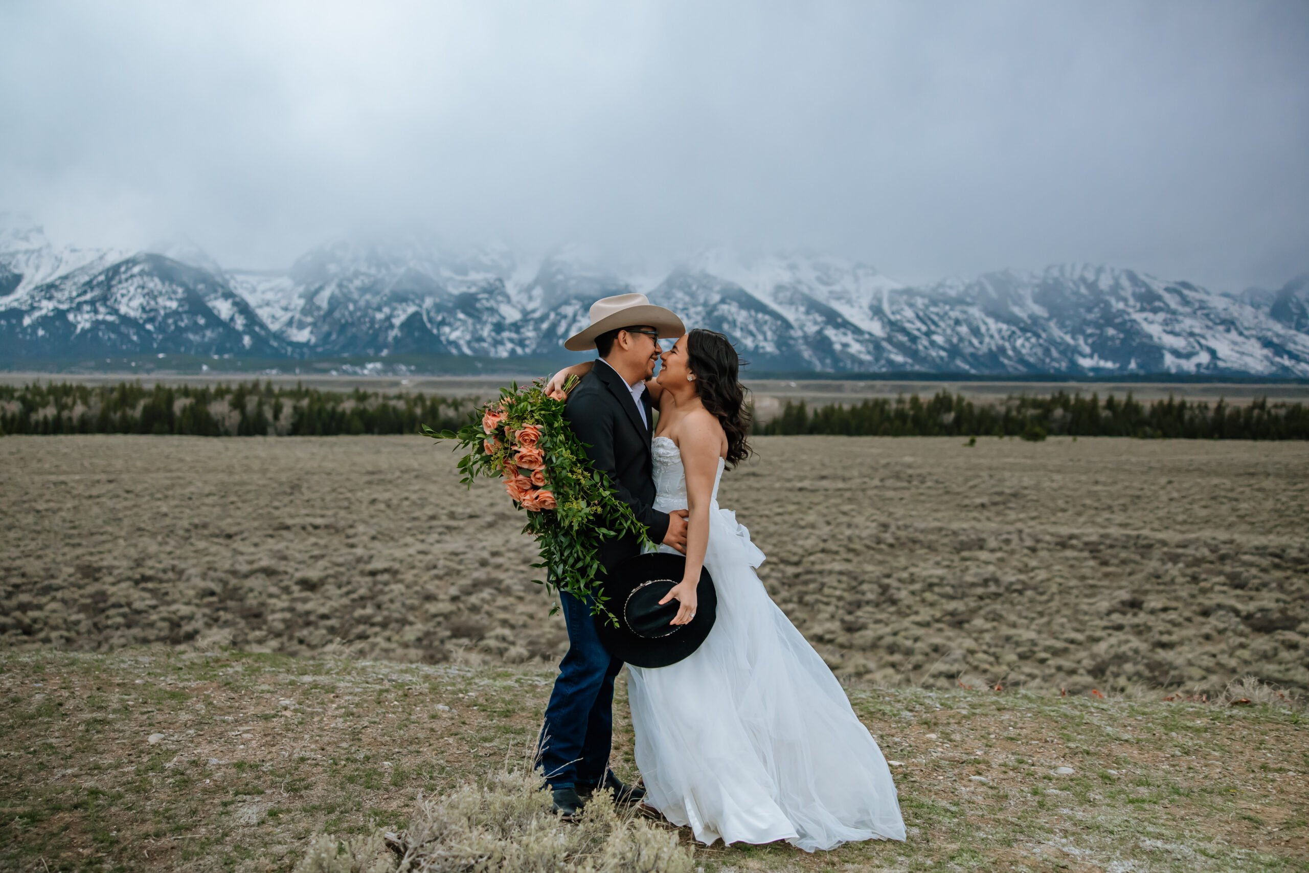 A bride and groom kissing with a mountain view as the background